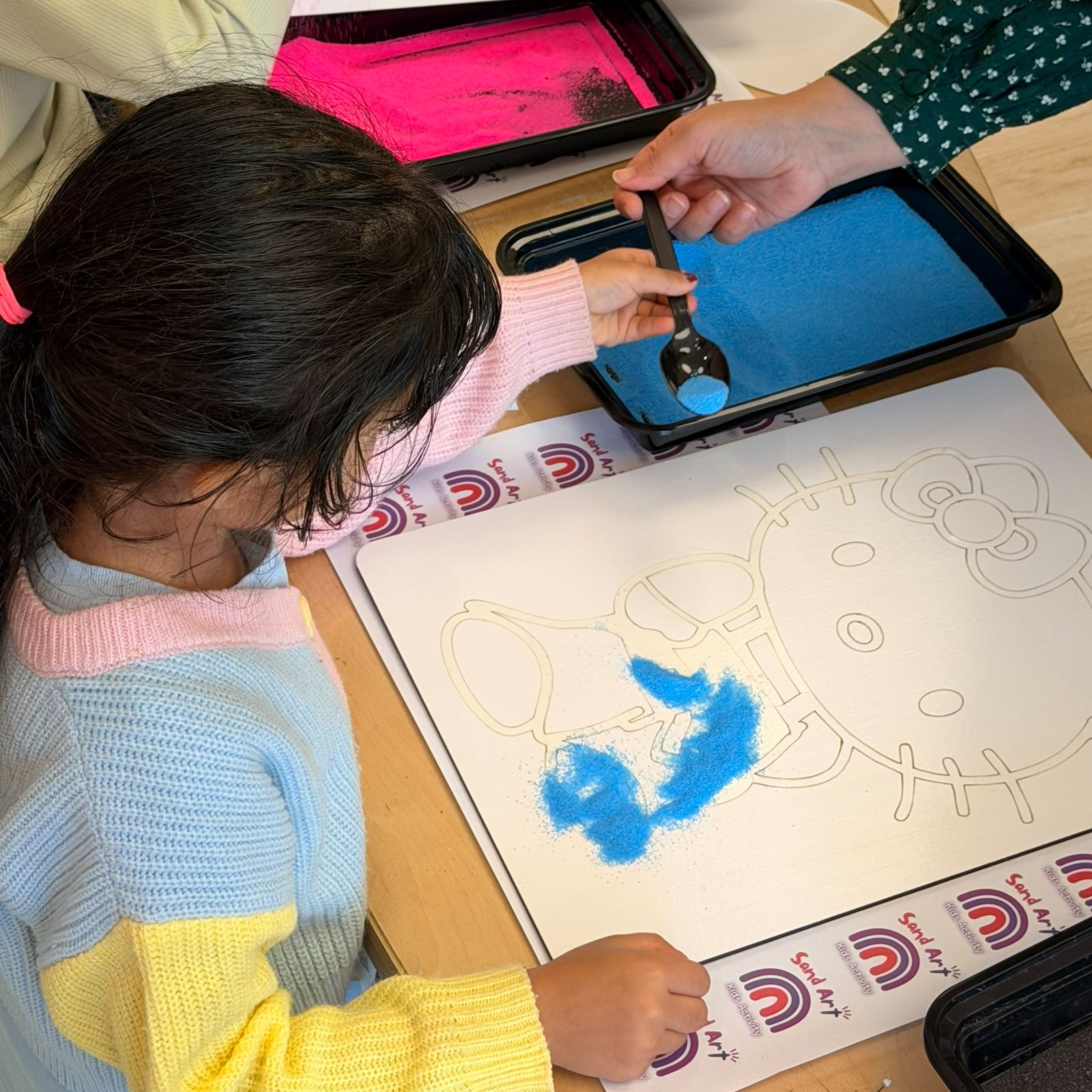 Child creating a blue sand painting